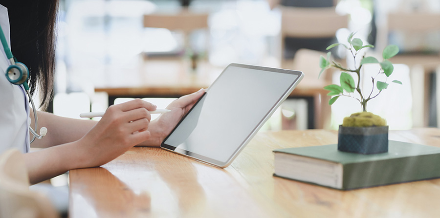 Canva Person Leaning On Wooden Table Holding White Tablet 1
