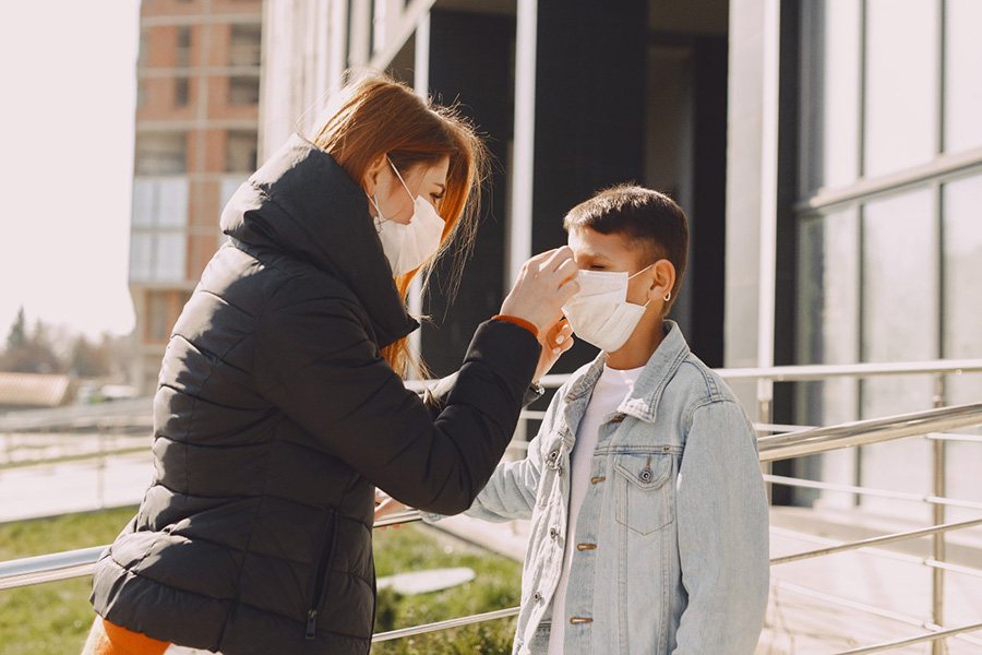 Canva Woman fixing protective mask on kid face